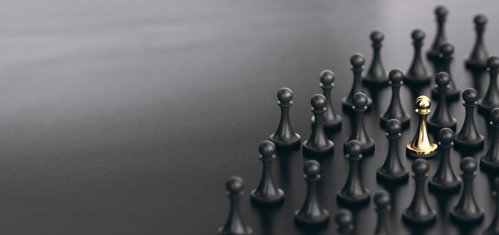 A silver chess pawn standing out among dark pawns